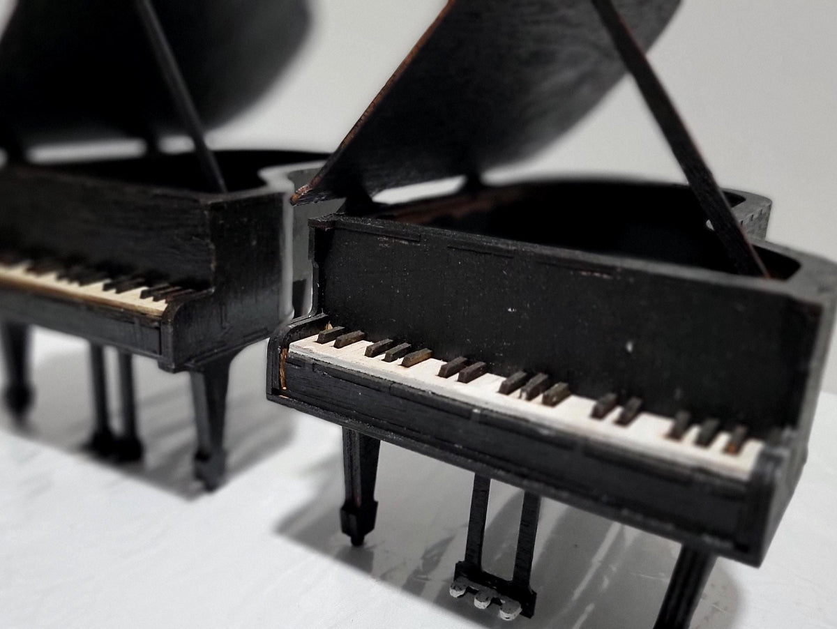 Looking for a distinctive gift for a pianist or music lover? This handcrafted jewelry box is a miniature replica of a classical grand piano — elegant, functional, and full of charm.
Made from solid MDF wood and finished in matte black with a thick polyurethane seal, it features realistic details: piano keys, pedals, and a lid that opens to reveal a jewelry compartment. We’ve reinforced the legs and foot pedals for added stability, and offer a double-thick lid option to prevent warping over time.