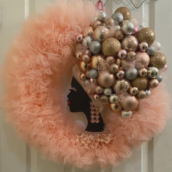 Decorative wreath with pink feathered edge and ornamented hair on a white door