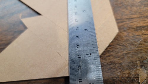 Metal ruler on a piece of brown paper with visible measurement markings on a wooden surface. DIY Cardboard Corner Protectors – Save Your Poster & Your Wallet!
You printed the perfect poster. Now protect it like a pro—without spending a dime on stock. These DIY cardboard corner protectors are made from scrap cardboard, turning trash into treasure and keeping your artwork safe from dings, dents, and disaster. Nothing worse than having that job done and someone bumps the corner, destroying the print you worked