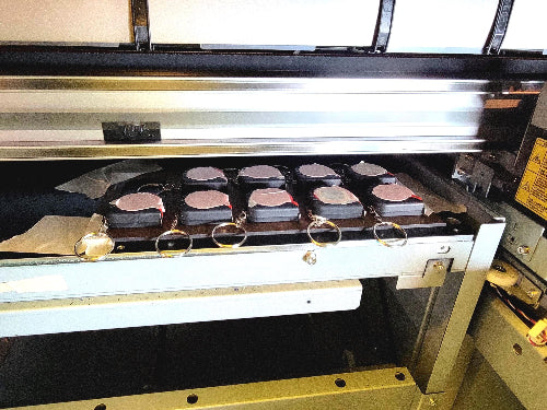 An automated machine with multiple small containers on a conveyor belt. I used my laser to cut 1-inch removable sticky paper. Then I placed a sticker on each test run to check position. After the test, I peeled off the label.
DIGITAL FILE__Use the Mutoh 661 UV Printer and CompressRip setup to ensure that your mini tape measures are securely held during the printing and handling phases. For added protection, consider using a material that’s both ink and UV-resistant, like coated plywood or MDF with a 