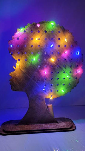 Decorative lamp shaped like a head with colorful lights on a reflective surface.