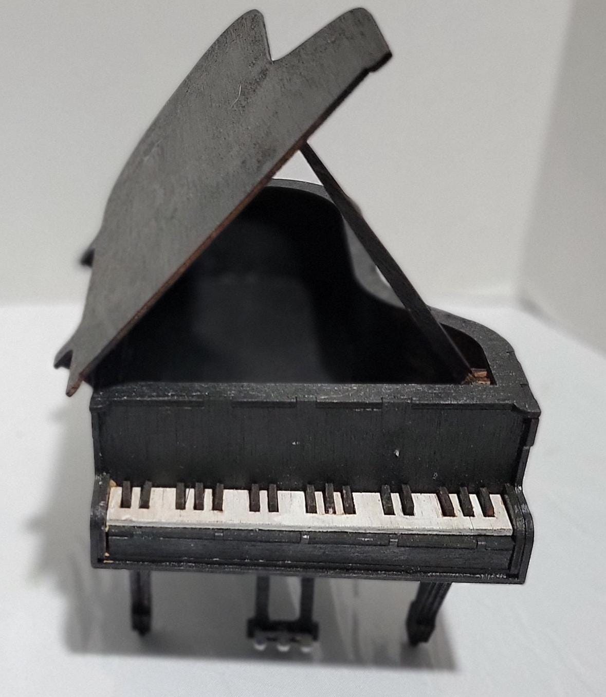 Don’t Miss This One-of-a-Kind Heirloom for Music Lovers
This isn’t just a gift — it’s a showstopper. A handcrafted miniature grand piano jewelry box that captures the soul of a concert hall in the palm of your hand. Designed for those who cherish music, memory, and craftsmanship, this piece is as rare as it is refined.
Meticulously made from solid MDF wood and sealed in a rich matte black finish, it features lifelike piano keys, pedals, and a hinged lid that opens to reveal a hidden jewelry compartment. 