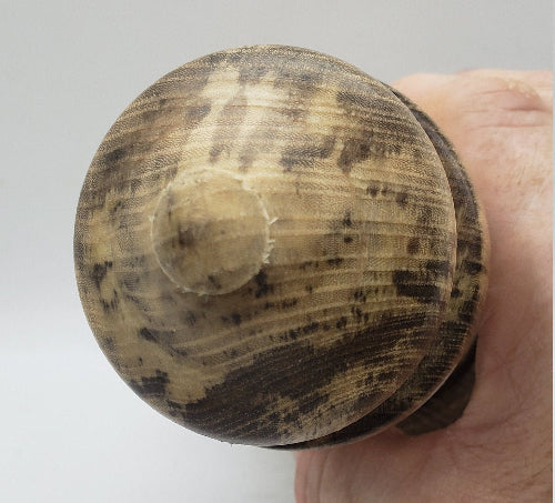 Close-up of a hand holding a textured wooden object against a plain background